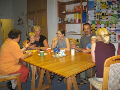 Foto von einer Elterngesprächsgruppe, an der drei Mütter, ein Vater, zwei Kinder und die Gesprächsleiterin teilnehmen
