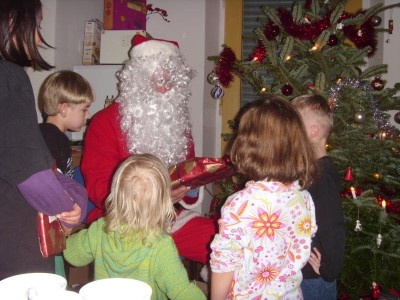 Foto von der Weihnachtsfeier für Eltern und Kinder 2013, der Weihnachtsmann verteilt unter dem Weihnachtsbaum Geschenke an die Kinder